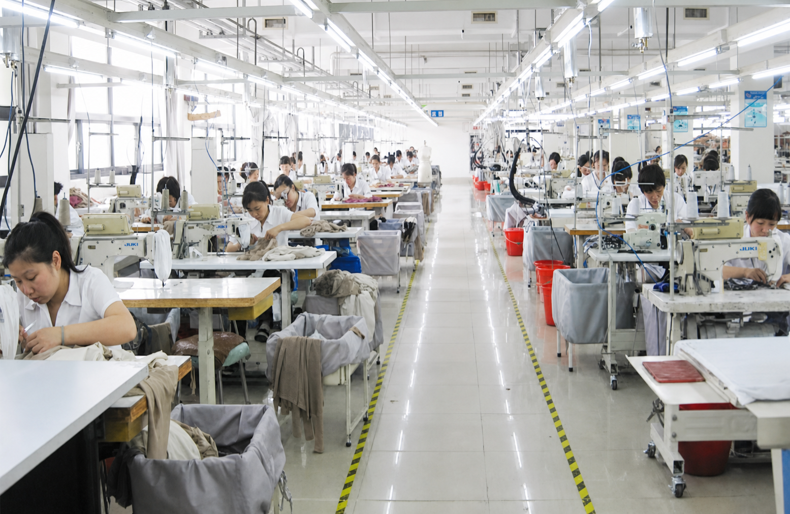 Active garment production floor with workers operating industrial sewing stations