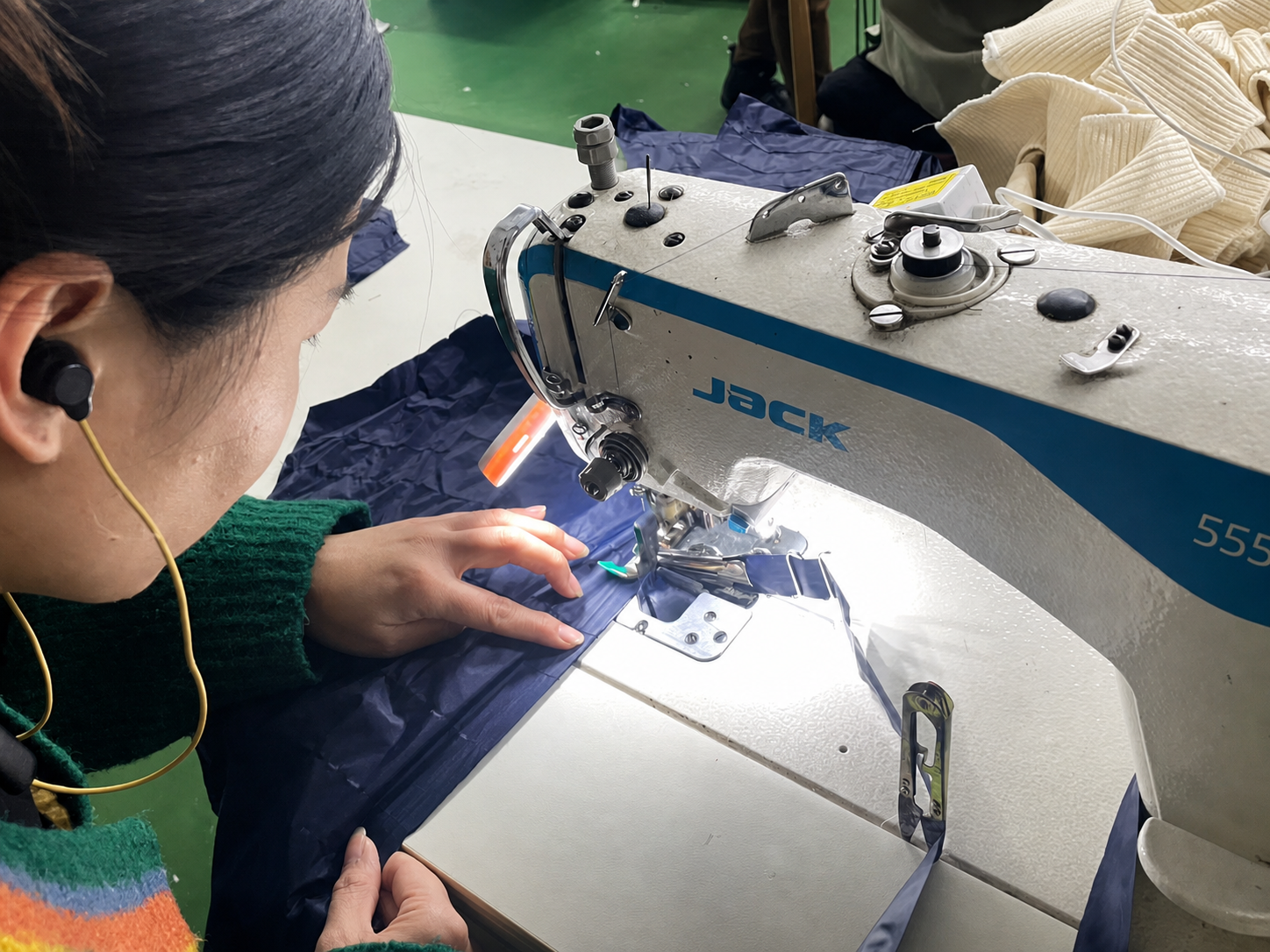 Garment worker sewing approved components during active production